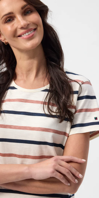 Smilende kvinde iført Redgreen T-shirt med brede marineblå og terracotta striber – afslappet og moderne sommerlook i blød bomuld. Perfekt til hverdagsbrug eller feriestemning ved kysten.